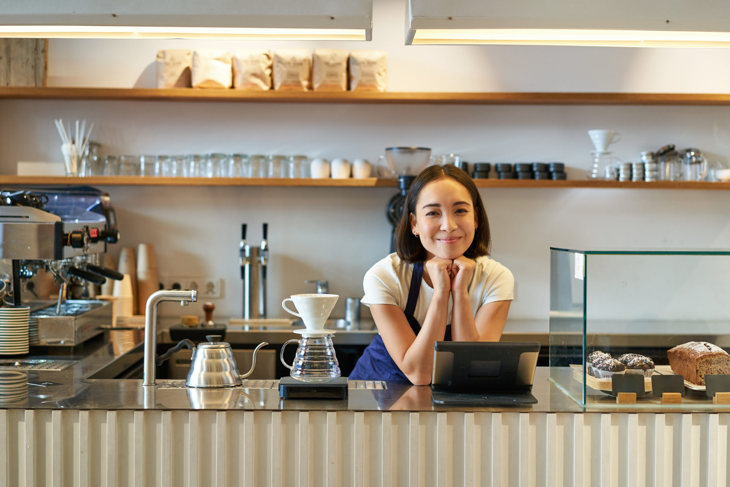 Small business owners. Smiling asian girl barista, standing at counter with filter coffee brewing kit and POS terminal, cafe and people concept